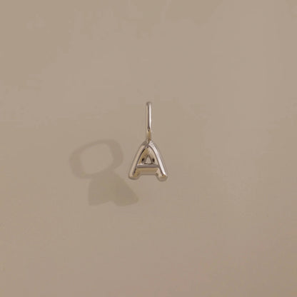 Silver 'A' letter pendant on a beige background