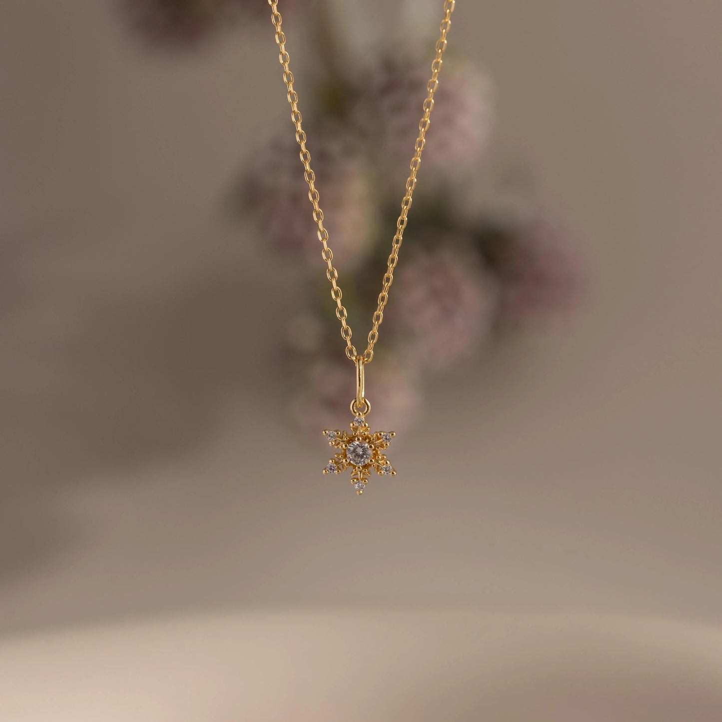 Gold necklace with a star-shaped pendant on a blurred background
