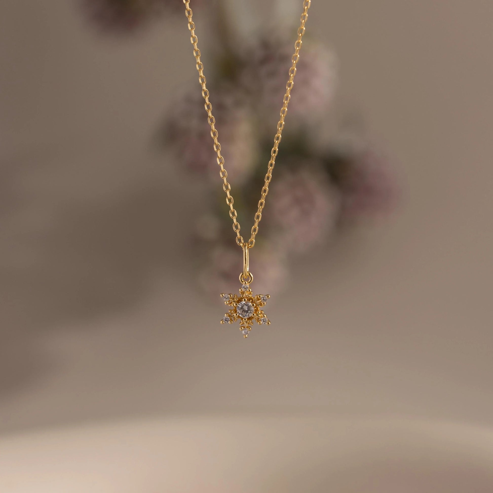 Gold necklace with a star-shaped pendant on a blurred background