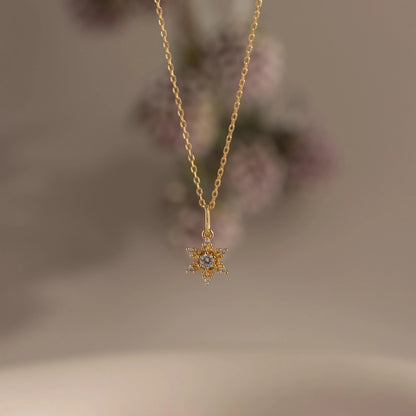 Gold necklace with a star-shaped pendant on a blurred background