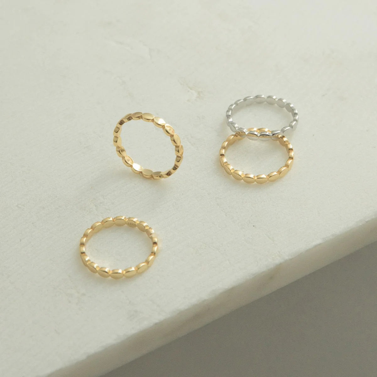 Three gold rings on a light gray surface