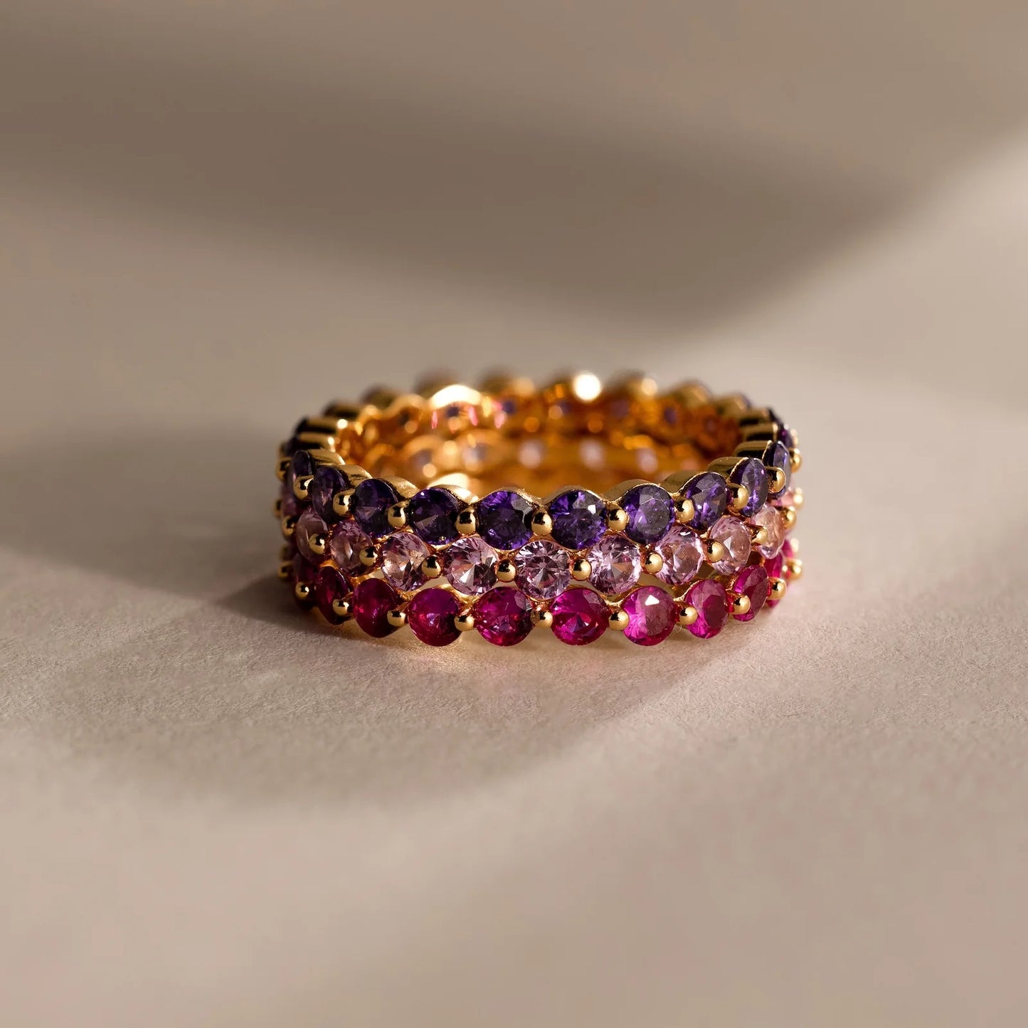 Gold ring with multicolored gemstones on a beige background