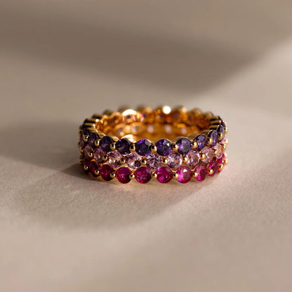 Gold ring with multicolored gemstones on a beige background