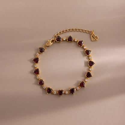 Gold bracelet with heart-shaped gemstones on a beige background