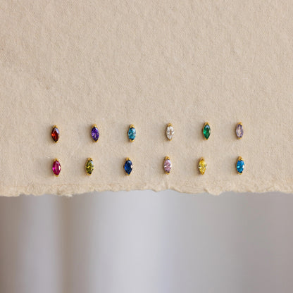 Row of multicolored gemstone earrings on a beige background