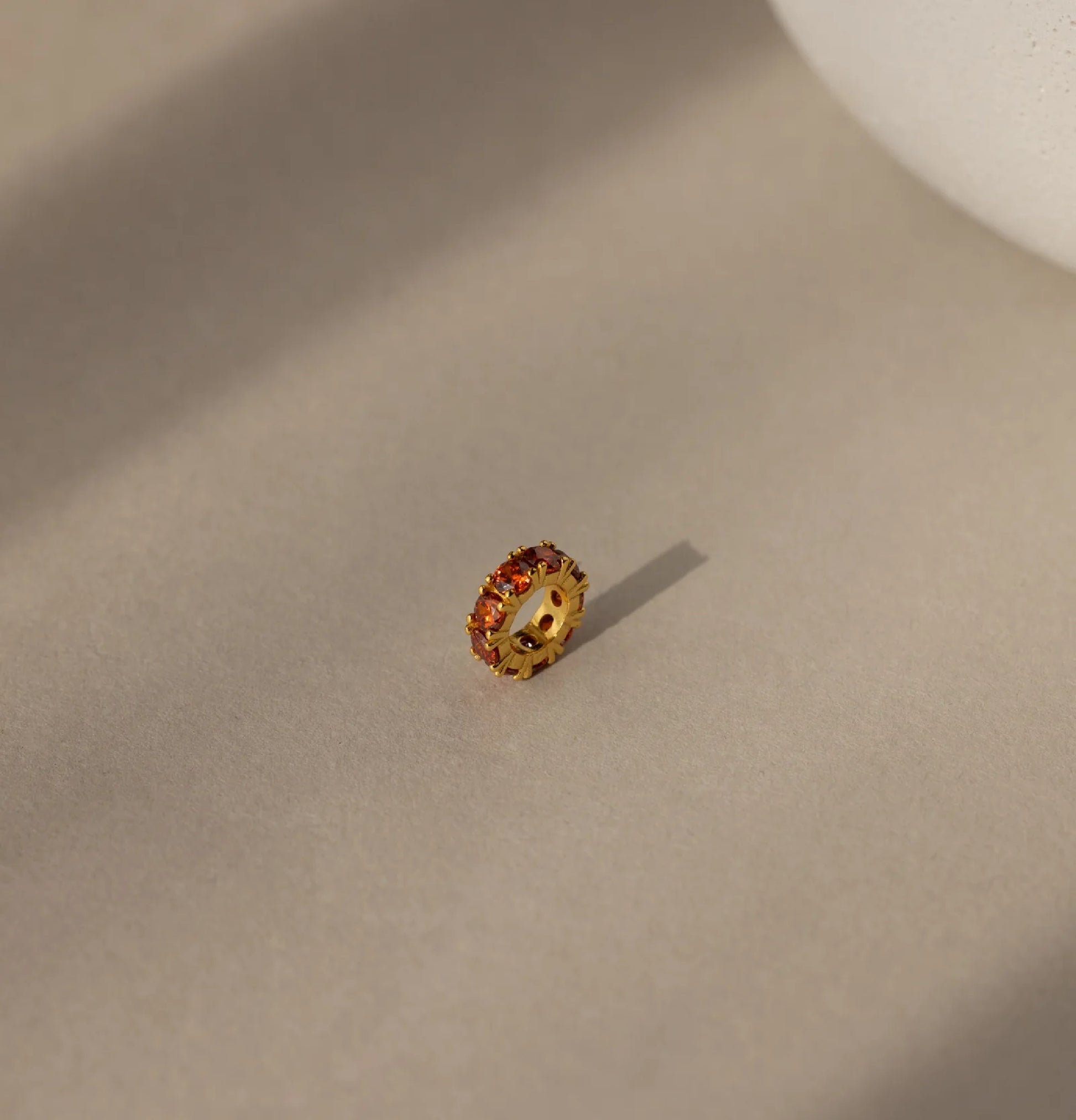 Gold ring with embedded stones on a beige surface