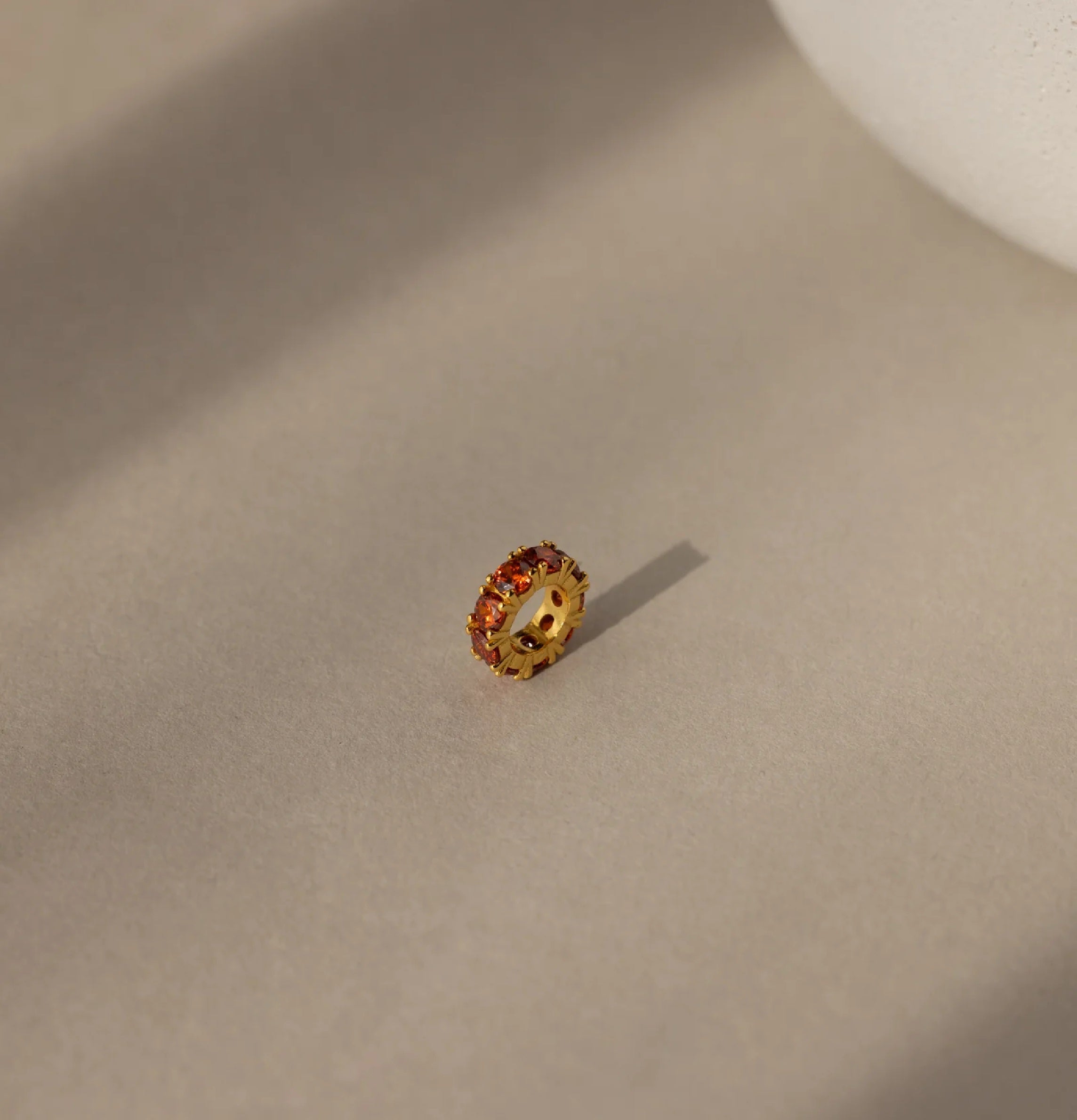 Gold ring with embedded stones on a beige surface