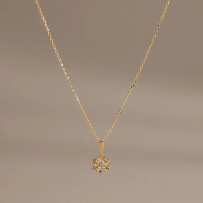 Gold necklace with a floral pendant on a brown background