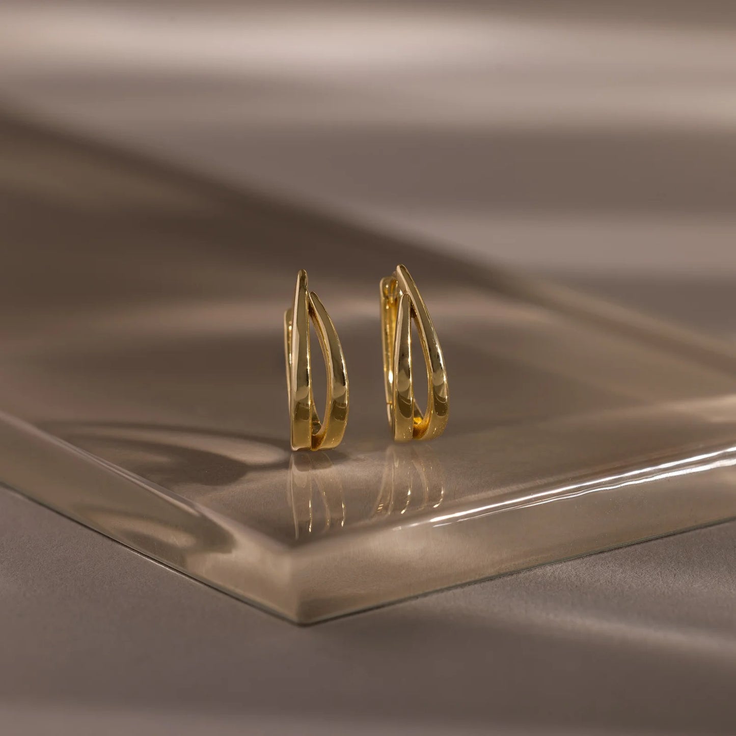 Gold hoop earrings on a reflective brown surface