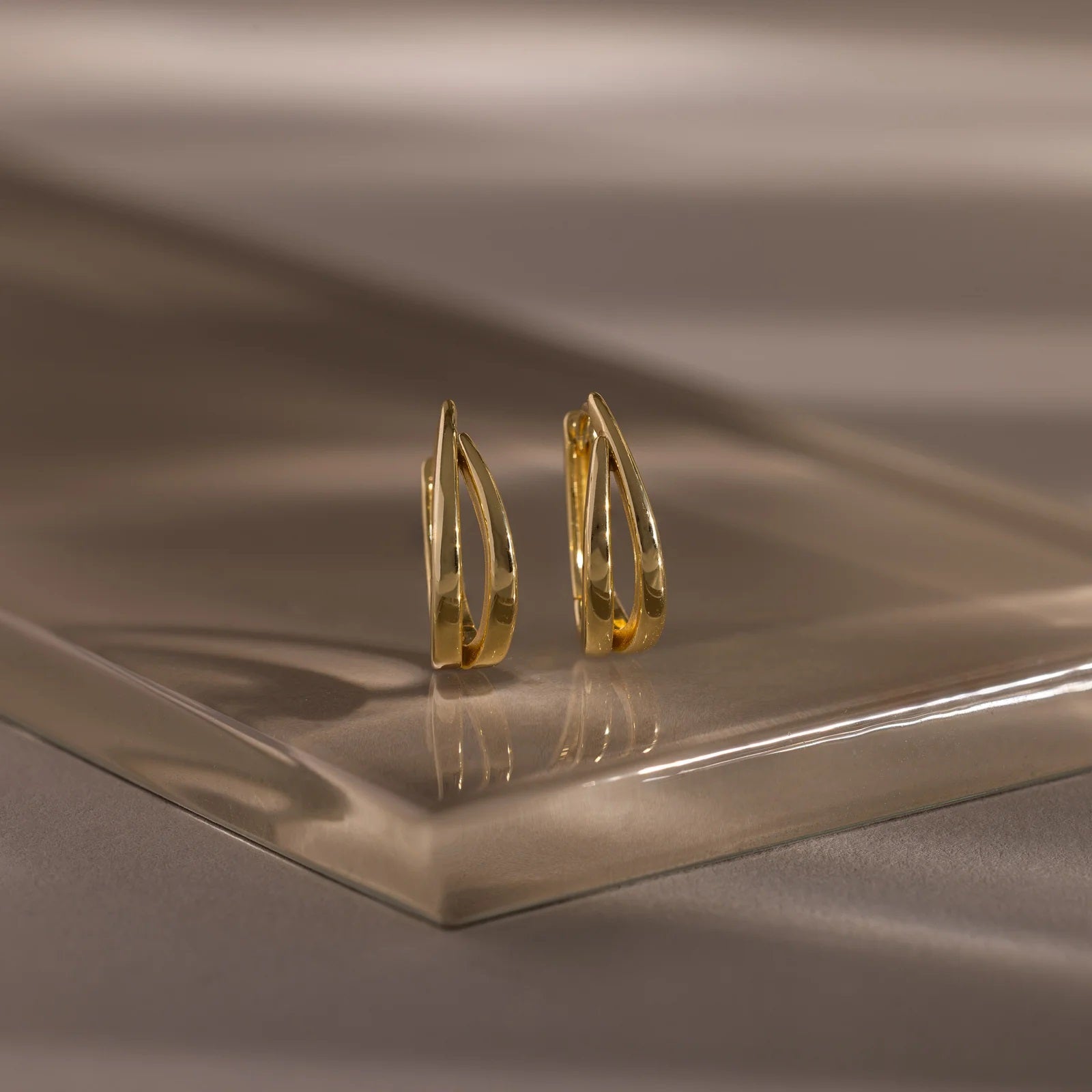 Gold hoop earrings on a reflective brown surface