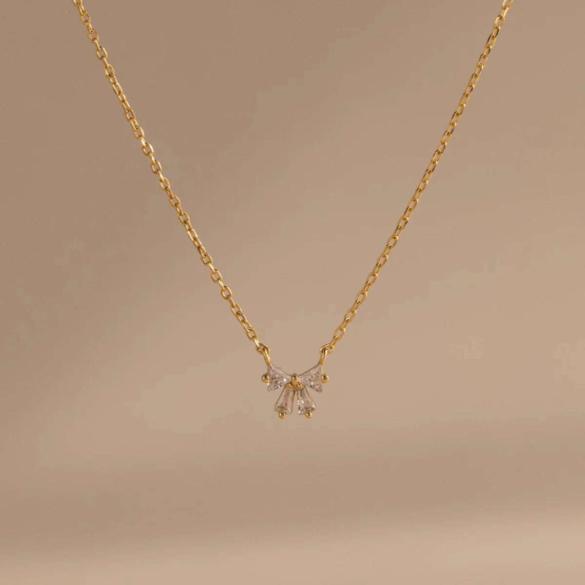 Gold necklace with a delicate pendant on a beige background