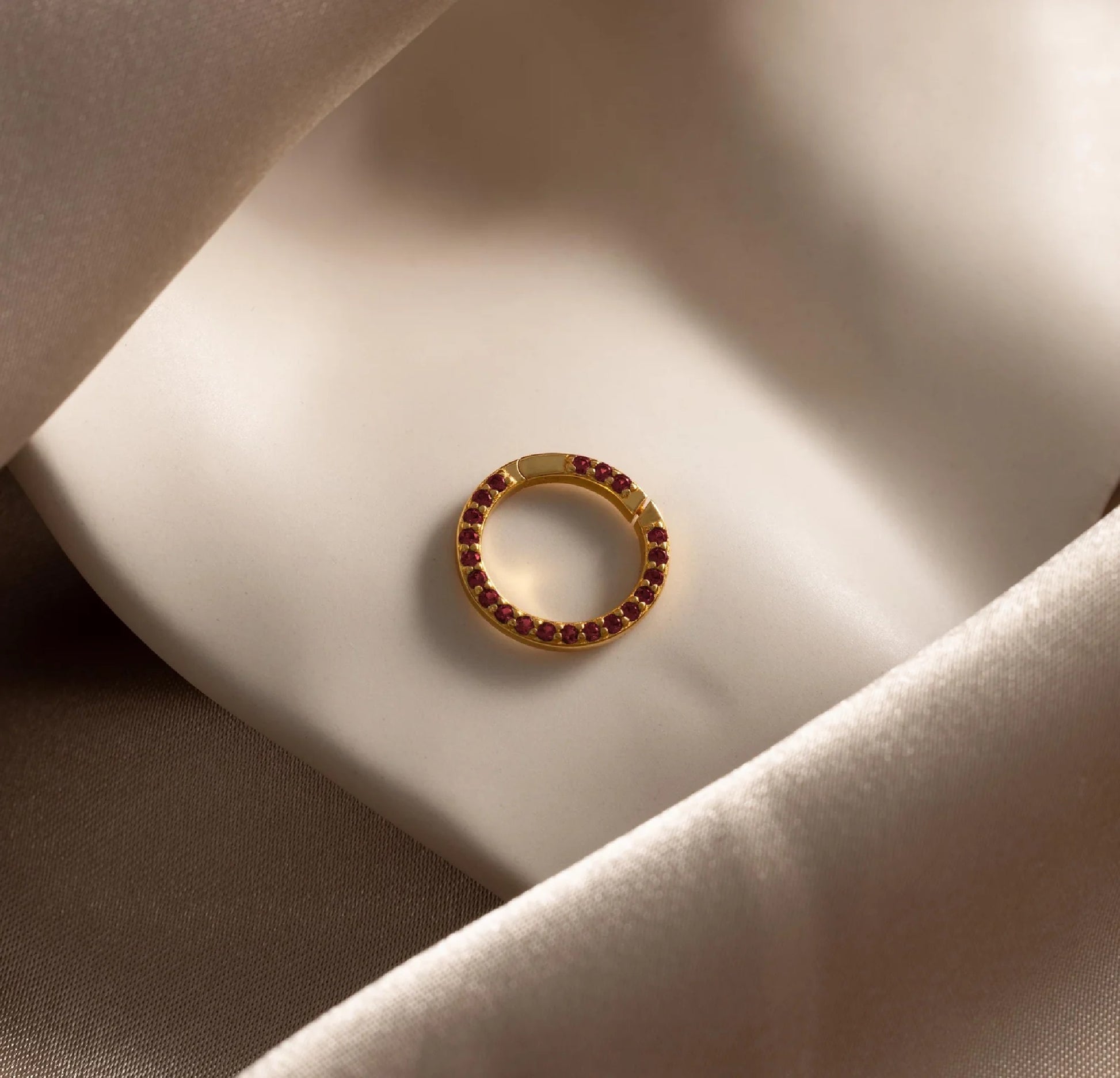Gold ring with red gemstones on a soft fabric surface