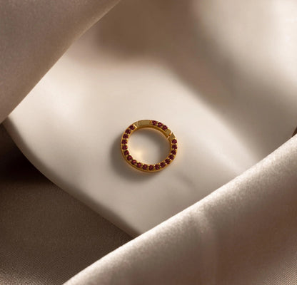 Gold ring with red gemstones on a soft fabric surface