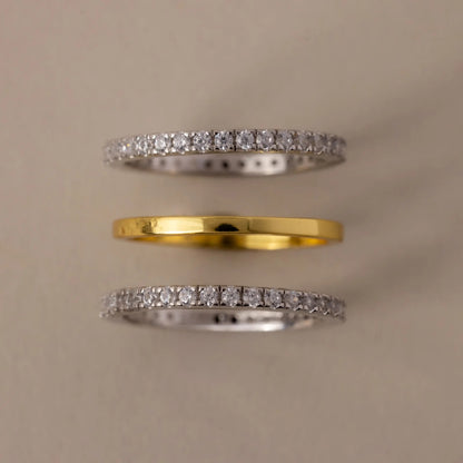 Three diamond-studded rings on a beige background
