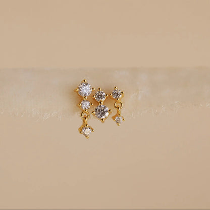 Gold earrings with clear stones on a beige background