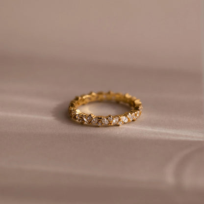 Gold ring with embedded diamonds on a beige fabric background