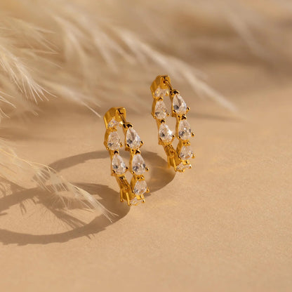 Gold hoop earrings with clear stones on a beige background