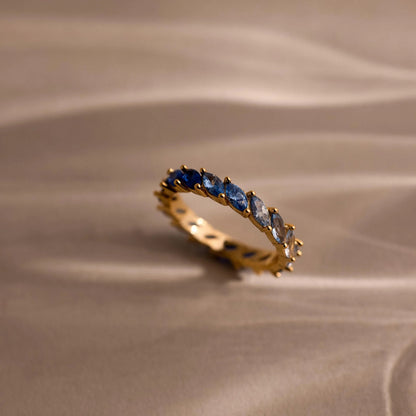 Gold ring with blue gemstones on a beige fabric background