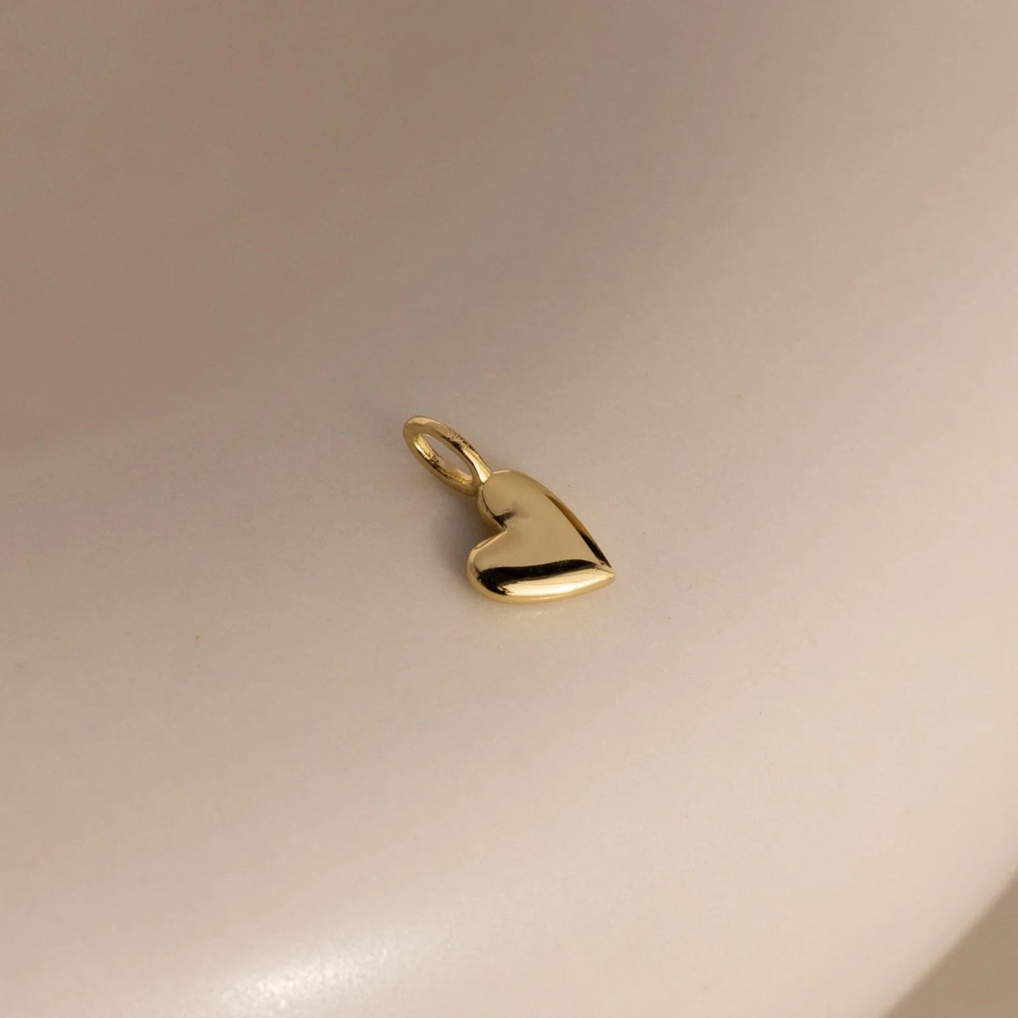 Gold heart-shaped pendant on a light beige background