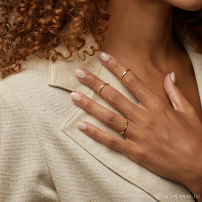 Close-up of a hand with gold rings on beige fabric, with 'EATLYN MINIMALIST' branding.
