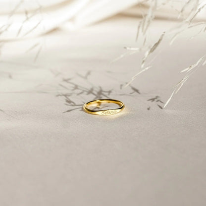 Gold ring with engraved text on a light beige background