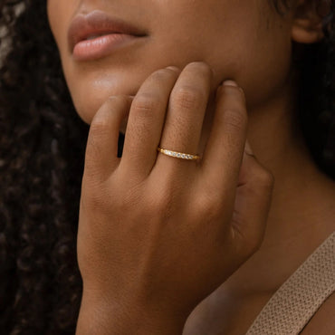 Close-up of a hand wearing a gold ring with a blurred background