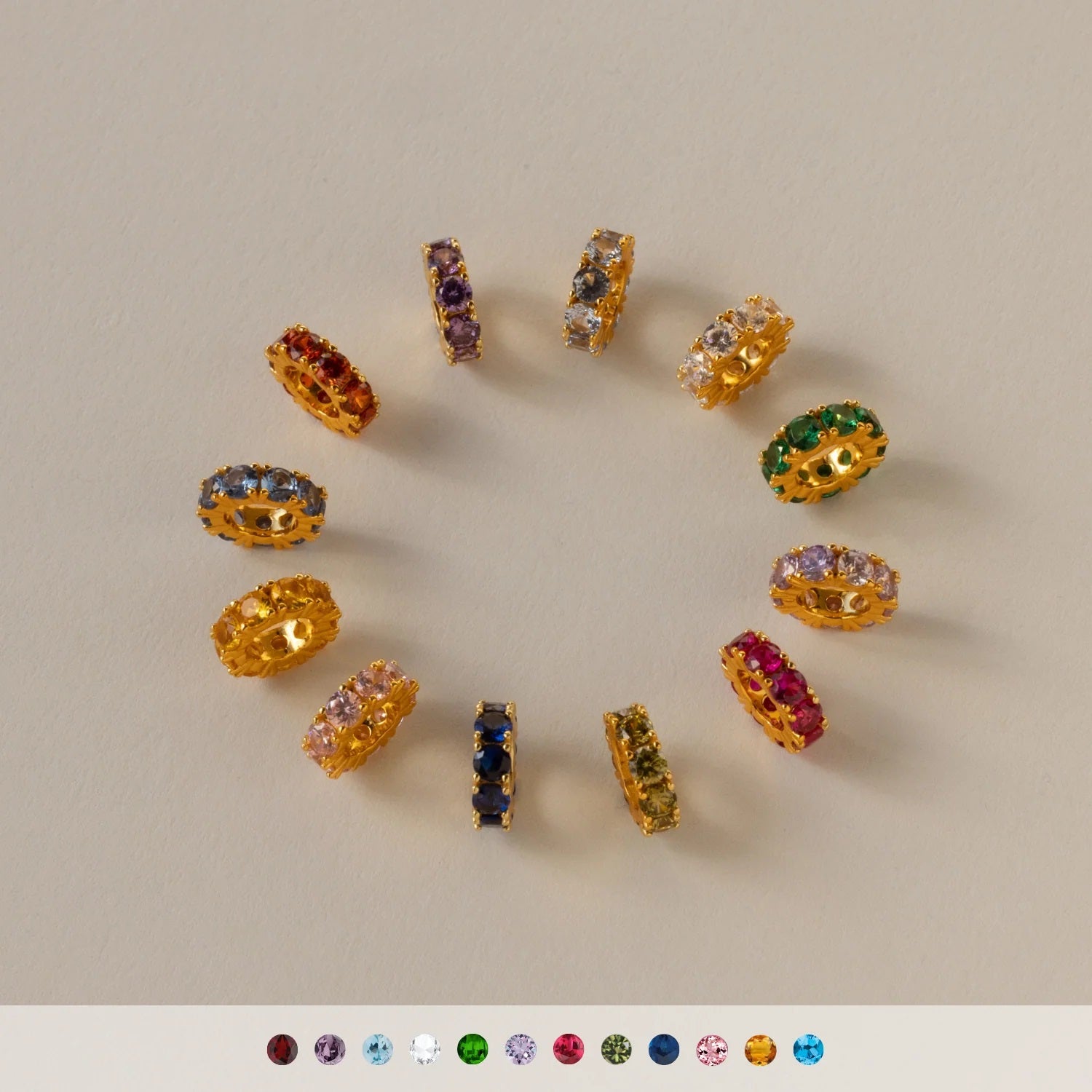 Gold earrings with multicolored gemstones on a beige background