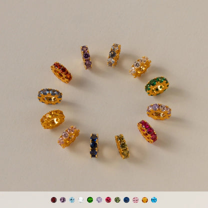 Gold earrings with multicolored gemstones on a beige background