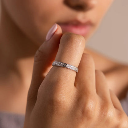 Close-up of a hand wearing a silver ring with a blurred background