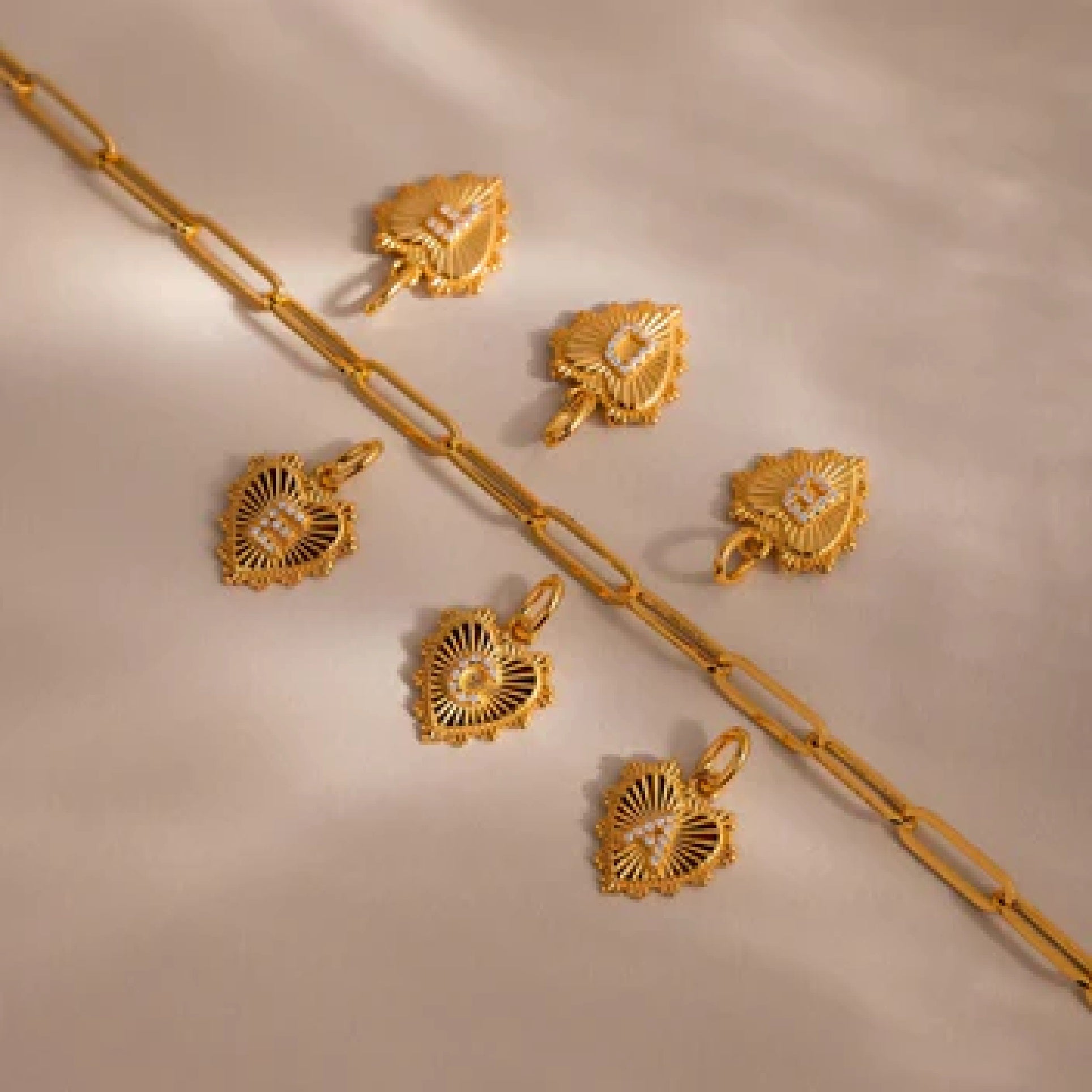 Gold jewelry set including necklace, pendants, and earrings on a beige background