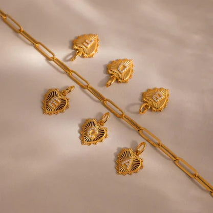 Gold jewelry set including necklace, pendants, and earrings on a beige background
