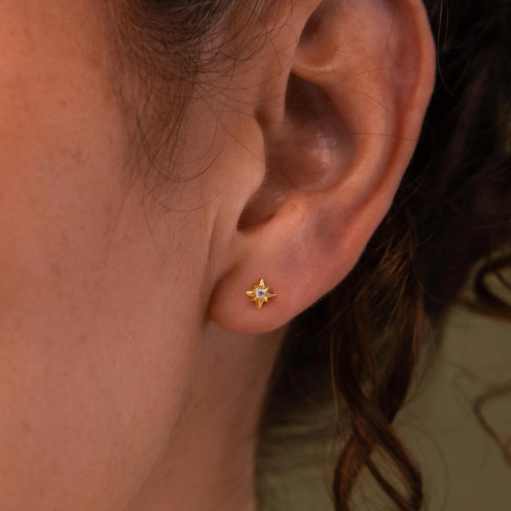 Close-up of an ear wearing a star-shaped earring with a blurred background