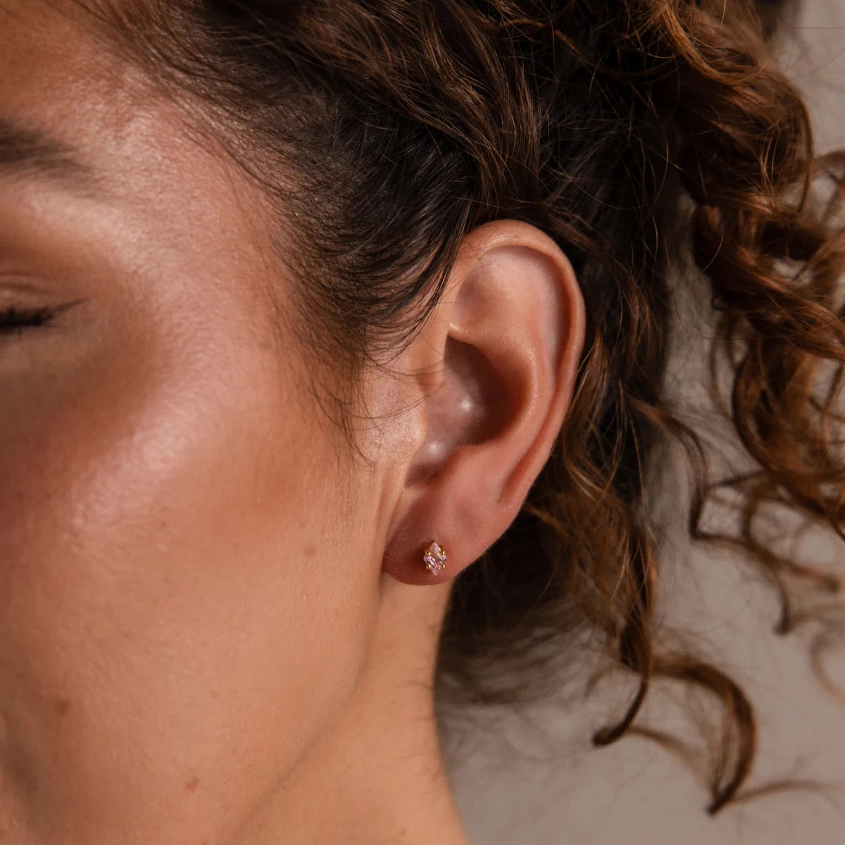 Close-up of an ear with a small earring, hair partially covering the face.
