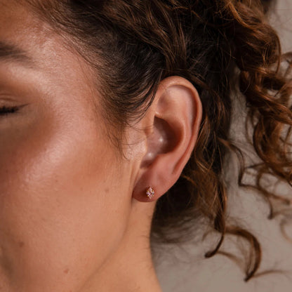 Close-up of an ear with a small earring, hair partially covering the face.
