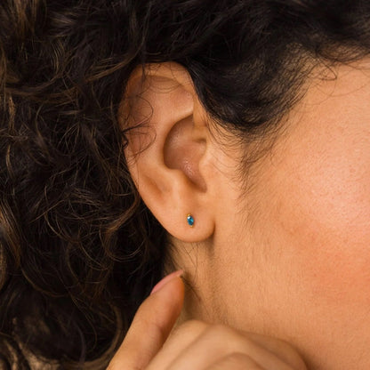 Close-up of an ear with a blue earring, hair partially covering the face.