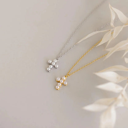 Two pearl necklaces, one gold and one silver, on a light background with leaves.