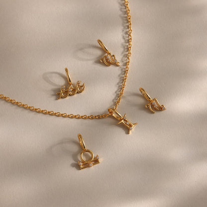 Gold necklace with matching pendants on a beige background
