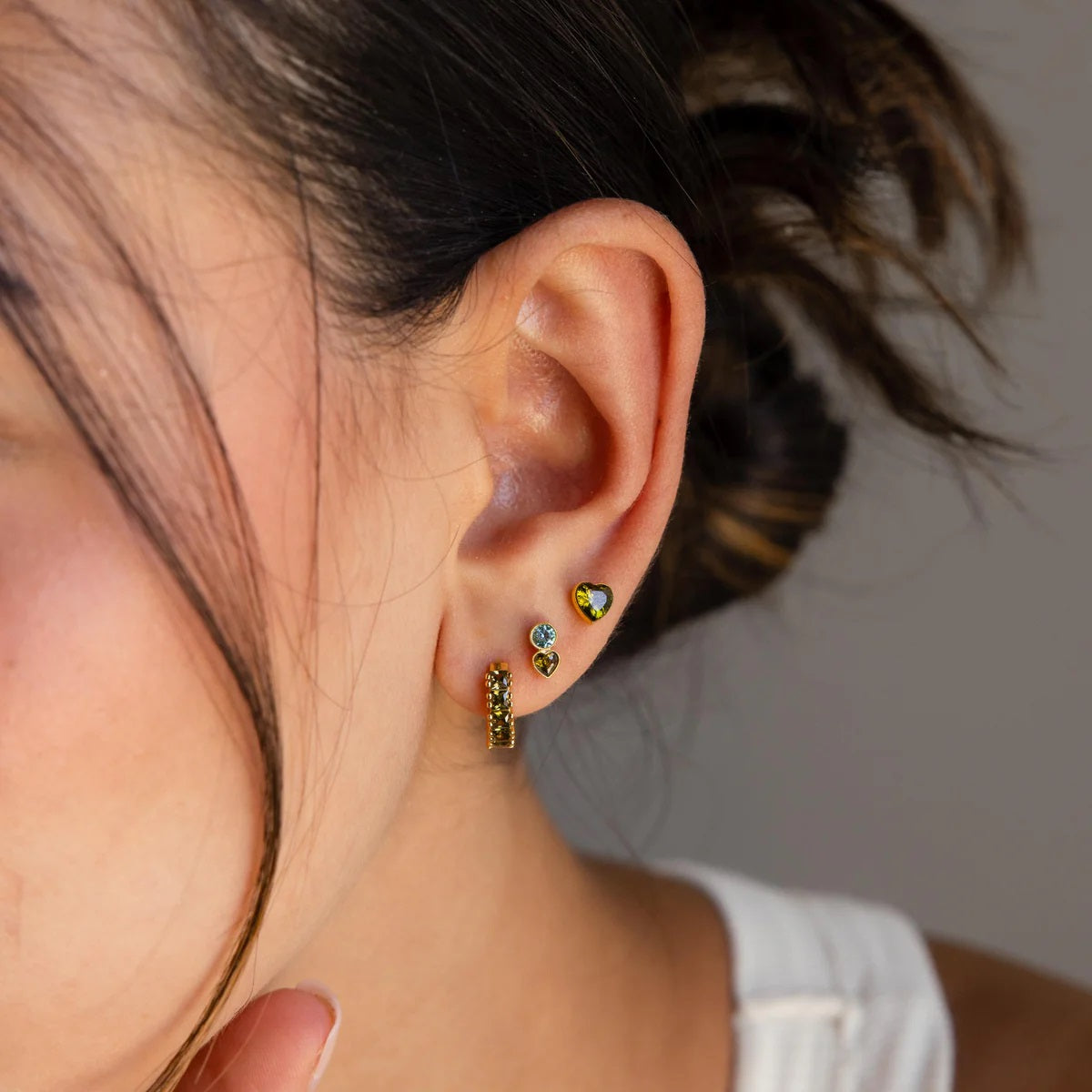 Close-up of a person wearing colorful earrings with a neutral background