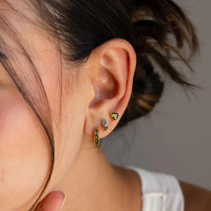Close-up of a person wearing colorful earrings with a neutral background