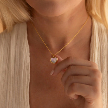 Gold necklace with a heart-shaped pendant worn by a person