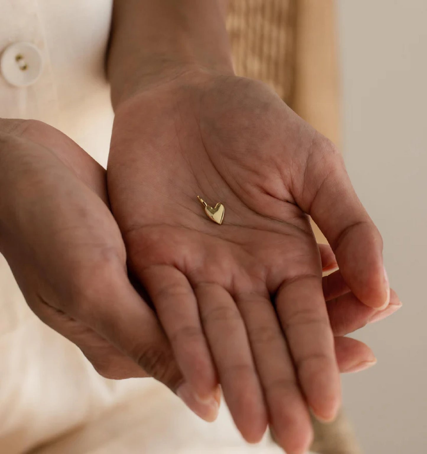 Gold heart-shaped earring held in a person's hand