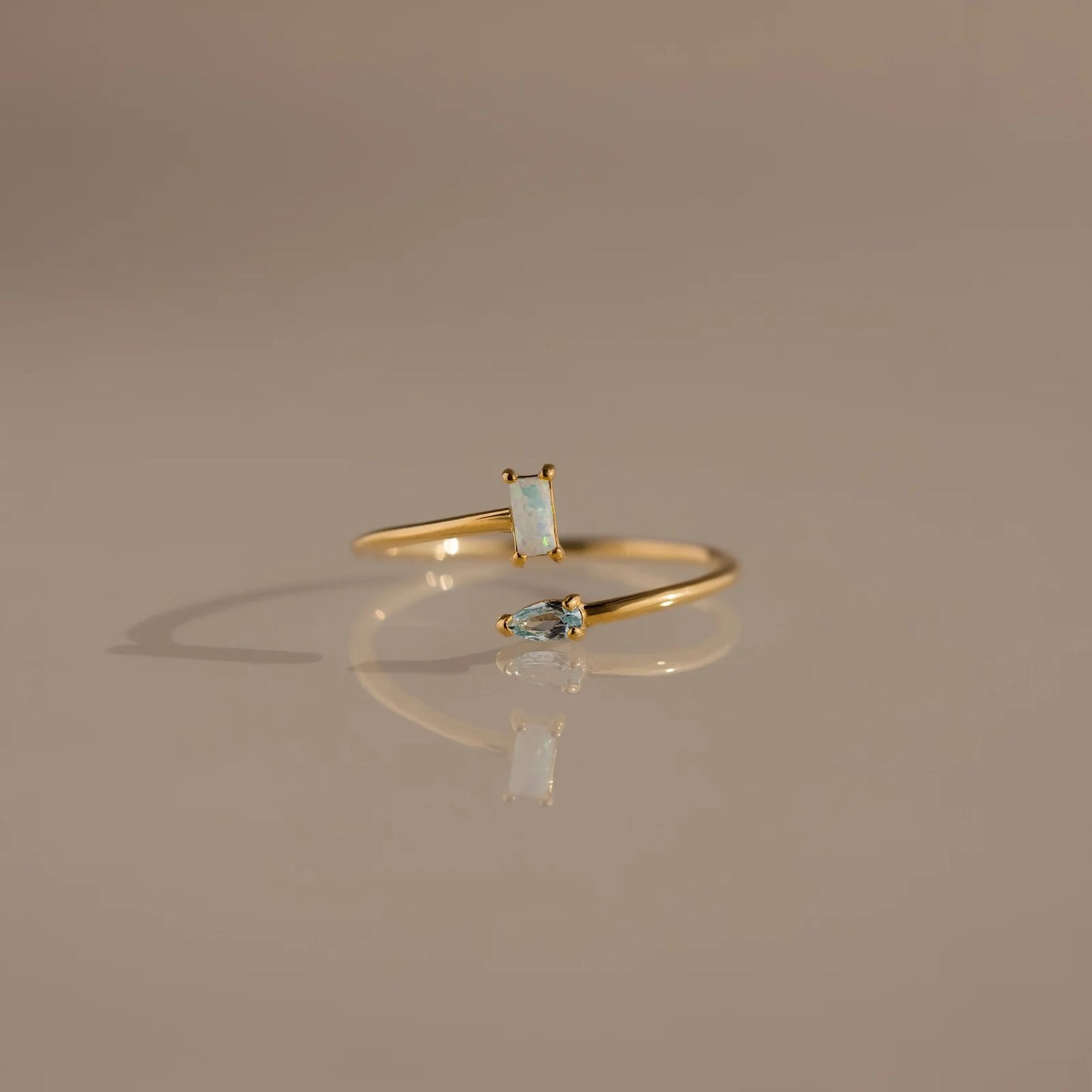 Gold ring with gemstones on a reflective surface