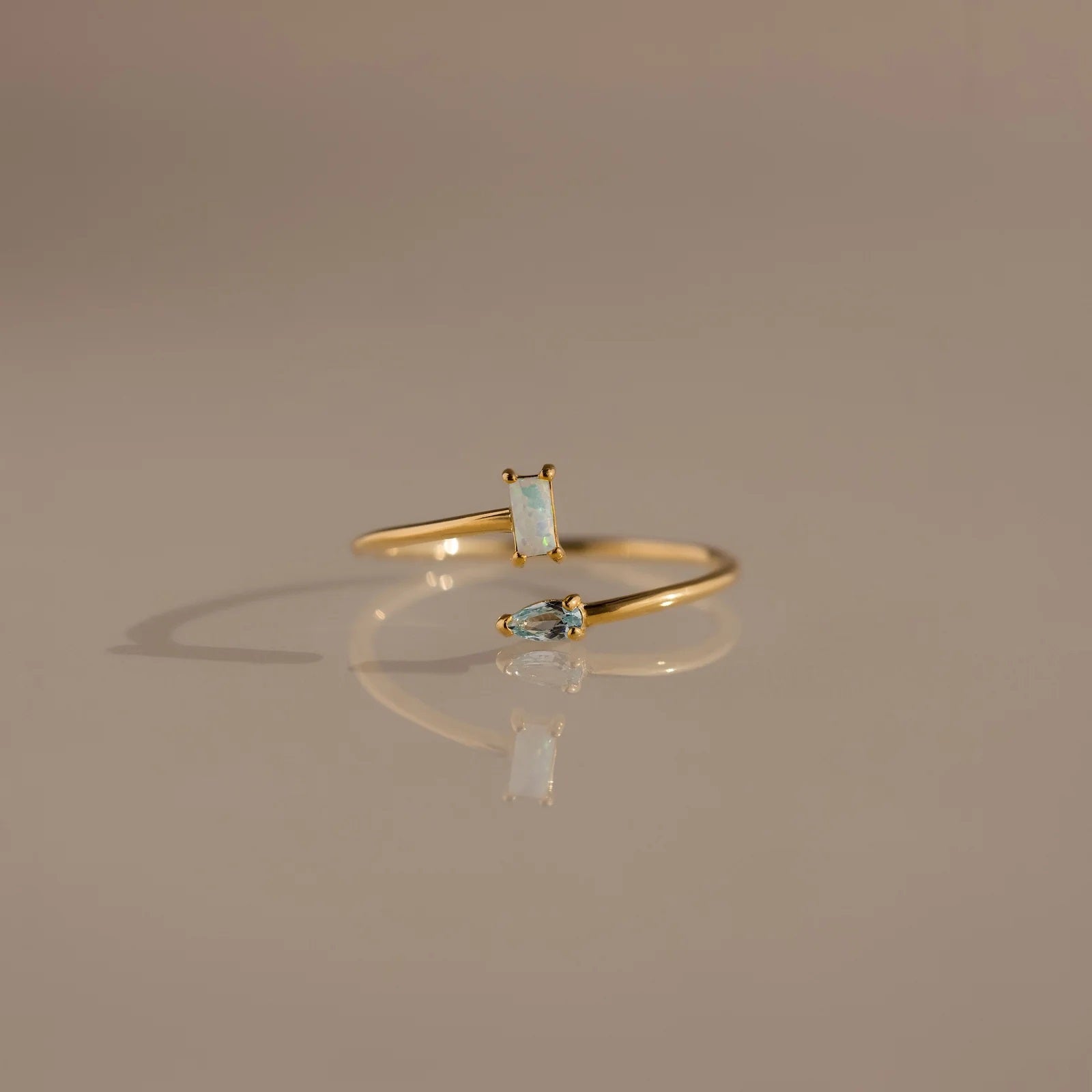 Gold ring with gemstones on a reflective surface