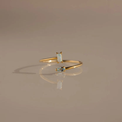 Gold ring with gemstones on a reflective surface