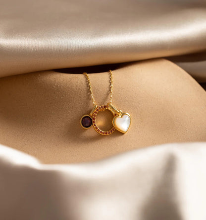 Gold necklace with heart and circle pendants on beige fabric