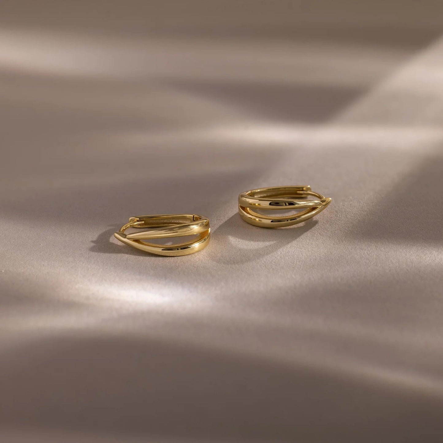 Two gold rings on a beige fabric background