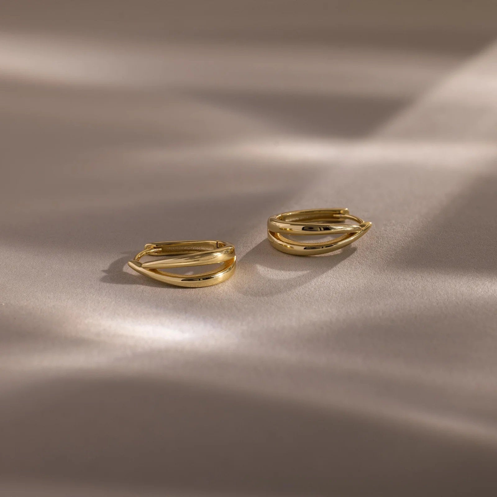 Two gold rings on a beige fabric background