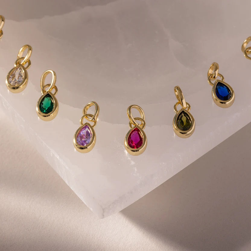 Gold pendants with colorful gemstones on a light background