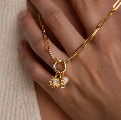 Gold chain bracelet with sun and moon charms on a hand against a neutral background