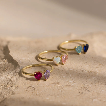 Set of gold rings with heart-shaped gemstones on a textured surface